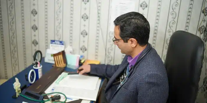 Parent et adolescent en consultation médicale avec documents de suivi