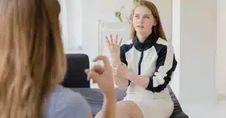 Personne penchée en avant, main près de l'oreille, écoutant attentivement une conversation
