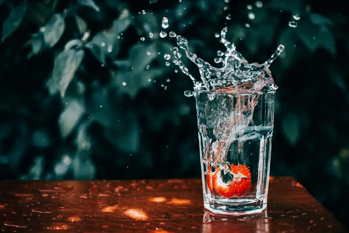 Verre d'eau et fruits frais sur une table, illustration de l'hydratation et de l'alimentation saine