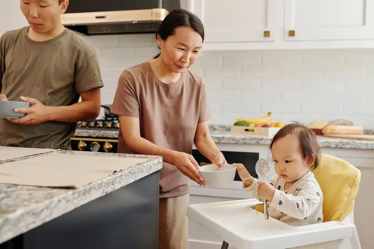 Mère préparant ses repas à l'avance tout en s'occupant de son bébé à proximité.