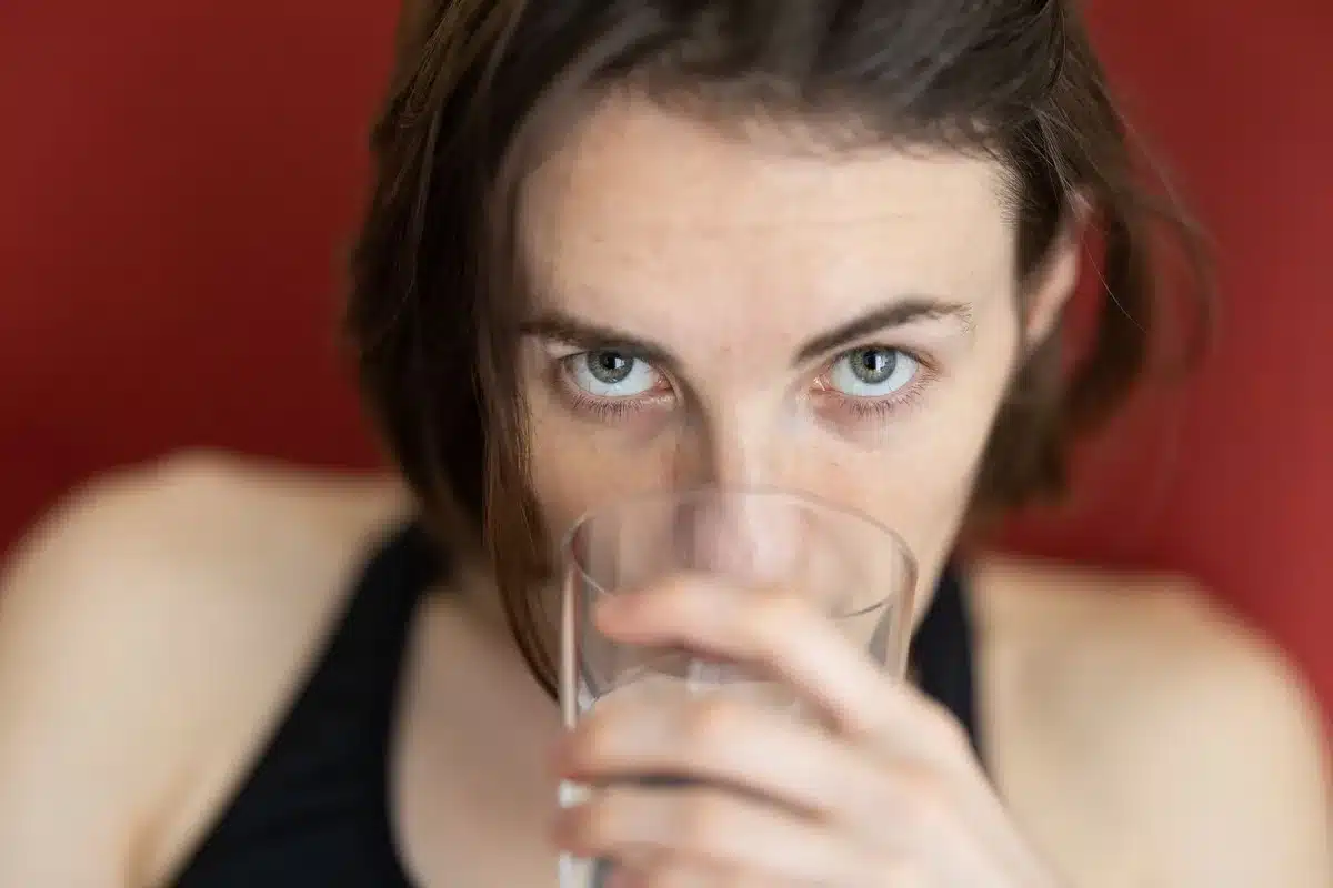 Personne buvant de l'eau régulièrement pour rester hydratée pendant l'été