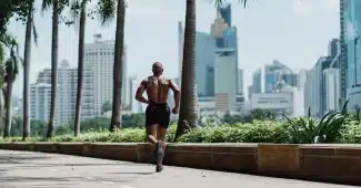 Coureur en vêtements légers s'entraînant sur un sentier ombragé par les arbres lors d'une matinée ensoleillée