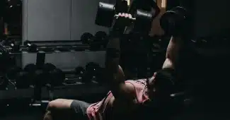 Personne effectuant un exercice de renforcement musculaire avec haltères en salle de sport
