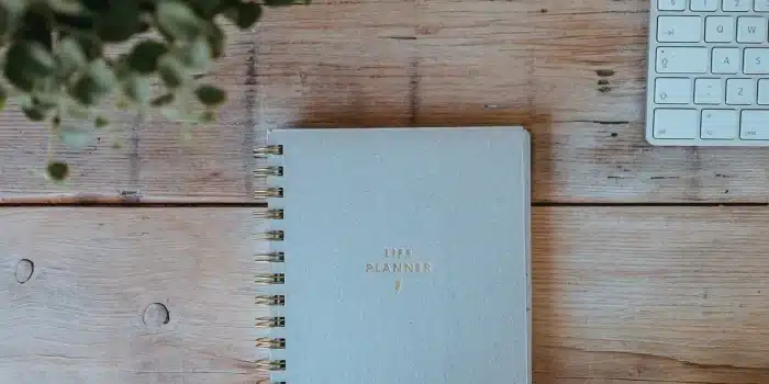 Table de cuisine en journée avec carnet de suivi et tasse, mains anonymes