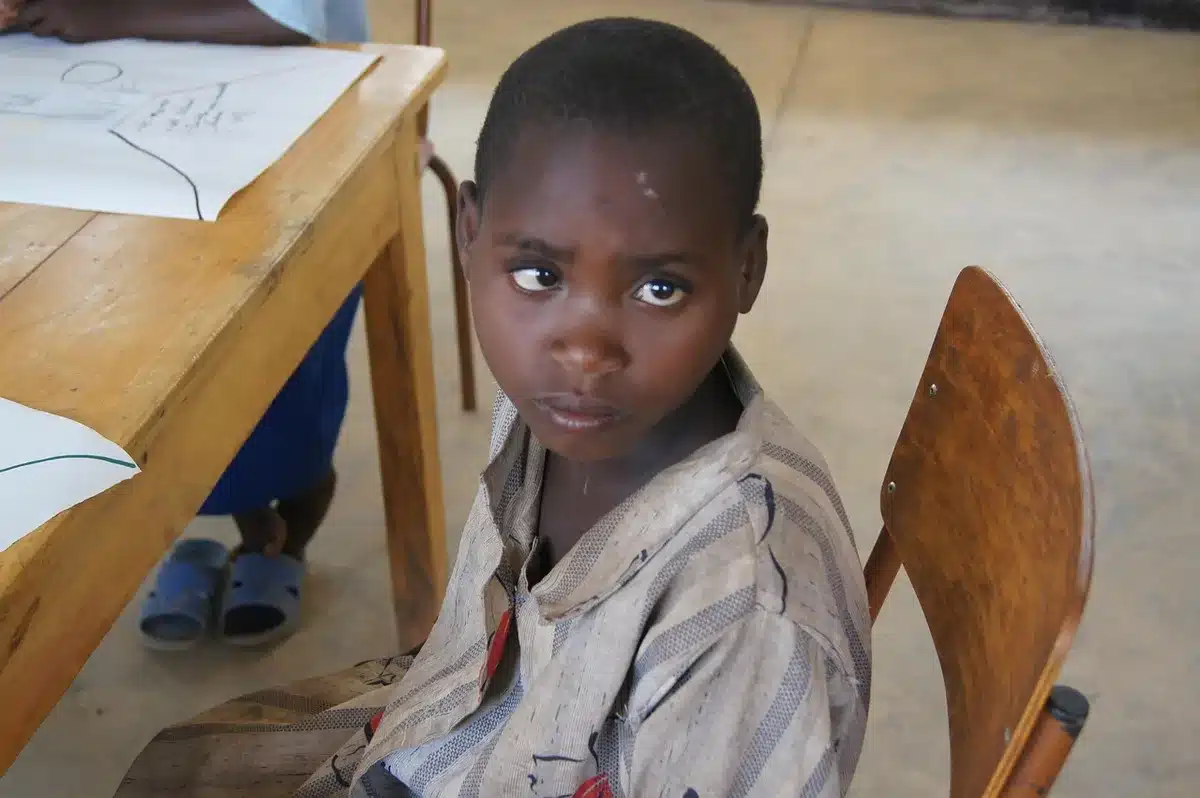 Enfant isolé assis à un bureau d'école, regard baissé