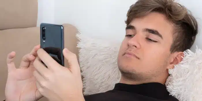 Adolescent regardant des vidéos culinaires sur son téléphone avec des aliments à proximité