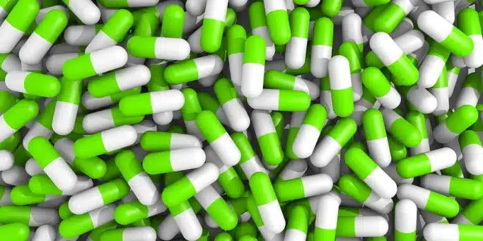 Mains anonymes près d'une pilule et dossiers médicaux sur une table éclairée par la lumière du jour