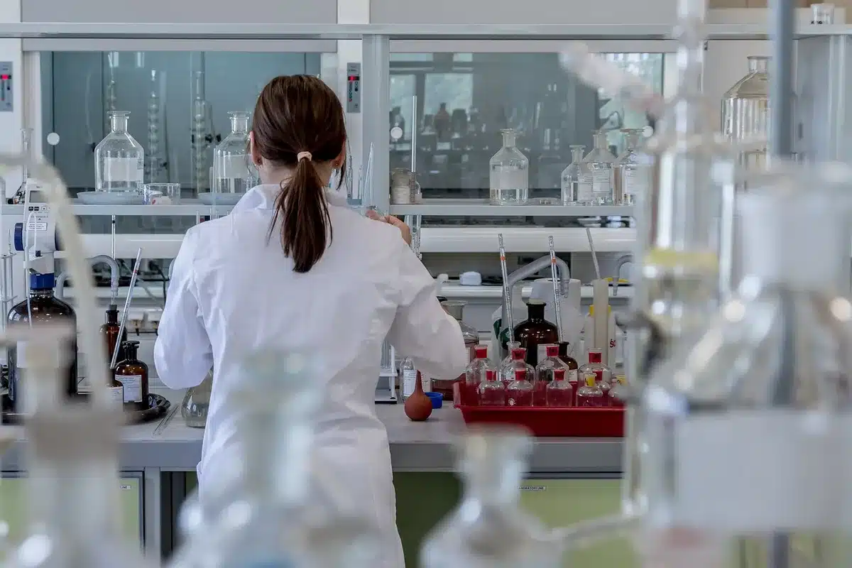 Mains gantées tenant un échantillon de fleur sur une table de laboratoire