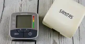 Tensiomètre posé sur une table près d'un carnet de suivi, mains anonymes à côté