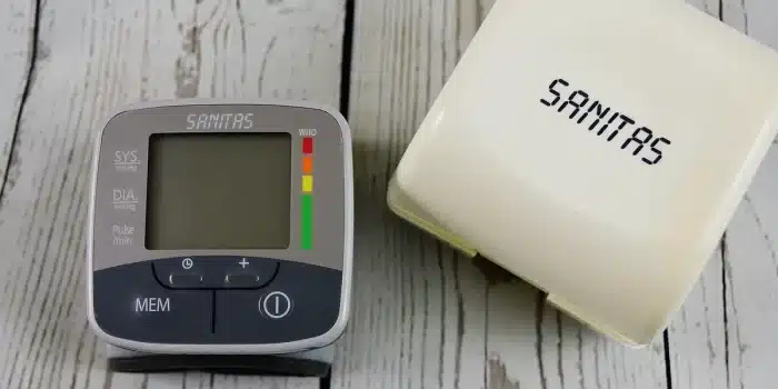 Tensiomètre posé sur une table près d'un carnet de suivi, mains anonymes à côté