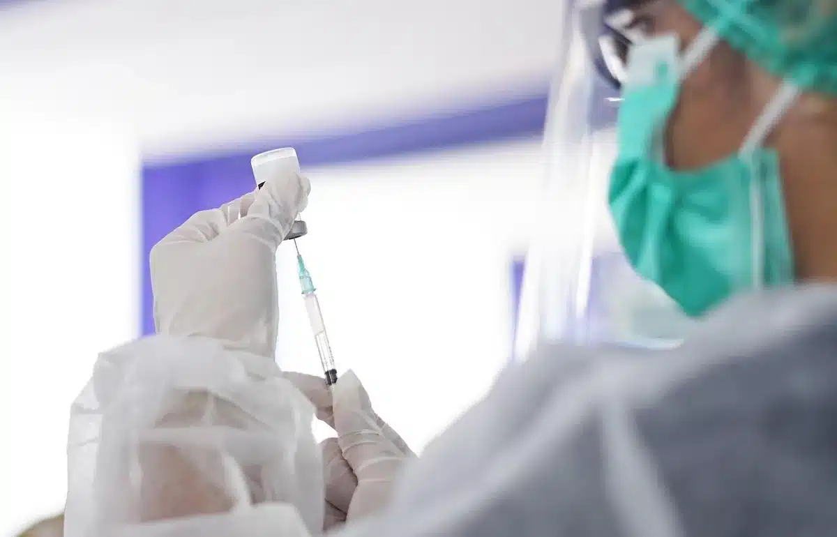 Bras recevant une injection avec du matériel médical en arrière-plan flou